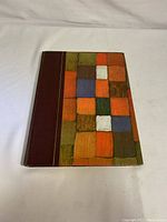 Front hardcover of the book showing colorful geometric pattern with maroon spine.