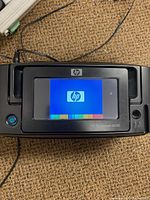 Front view of HP Photosmart A636 printer powered on showing HP logo on the touch screen.