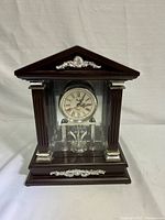 Full frontal image of Studio Quartz table top clock showing wood frame, decorative silver elements and clear glass front.
