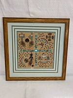 Full view of the framed Navajo sandpainting showing the matting and wooden frame with detailed sand art inside.