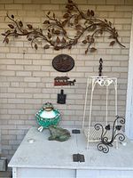 Wide view of the garden ornaments and plant stands displayed against a brick wall showing the arrangement and types of items included.
