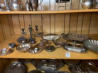 Wide view of shelf with assortment of bowls, trays, basket, candelabrum