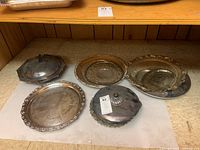 Overall set of silverplate trays and covered serving dish arranged on a countertop showing shapes and tarnish.