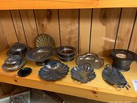 Overview photo of the silverplate collection showing various dishes, covered dishes, scallop shells, and crumbers on a wooden shelf with tarnish visible.