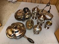 Overall view of teapot, coffee urn, sugar bowl, creamer, cup, ladles, tray, folding dish and relish dish on surface