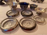 Full view showing five silver rimmed coasters in front and four footed bowls/dish in back