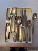 Overview of assorted flatware in box showing forks, spoons, knives