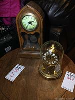Overview image of both clocks on a wooden table, showing size difference and general condition.