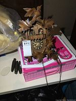 Front view of carved wooden cuckoo clock on table alongside pine cone weights and leaf pendulum
