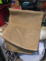Photo showing folded heavy woven jute rug with visible thick bound edging and textured weave pattern, highlighting overall size and appearance.