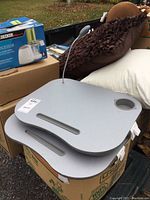 Top view of two gray lap tables stacked, showing drink holder cutout, grooves, and flexible light attached.