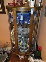 Front view of the oak curio cabinet showing curved glass panels and overall shape