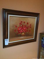 Framed painting of red flowers on a beige background, showing the full artwork and frame.