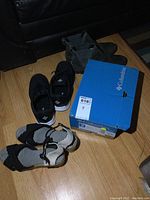 Photo showing all four pairs: black Columbia shoes in box, black Columbia running shoes, black and white wedge sandals, and grey Sorel boots.