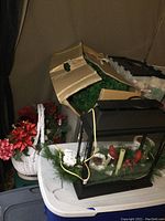 Overall lot showing the light up display case, artificial tree box, and floral arrangement in wicker basket on table.