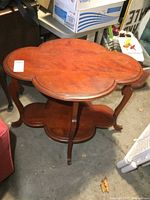 Photo of vintage solid wood side table with clover-shaped top and lower shelf from front