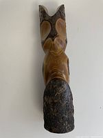 Top view of carved wooden owl sculpture showing smooth and polished wood combined with natural bark. The owl is stylized with simple carved features.