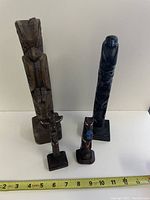 Four totem poles arranged with measuring tape showing sizes, front view