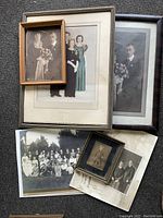 Group of framed vintage portraits and formal photos showing wedding couple, family, and individuals, various sizes and wood or metal frames.