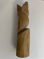 Side view of carved wooden owl on base, showing natural wood details and owl features.