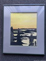 Front view of framed painting with gray mat and metallic frame. Depicts stylized landscape with trees and water on yellow-orange sky.