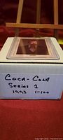 Box labeled 'Coca-Cola Series 1 1993 1-100' with trading cards in protective sleeves visible on top.