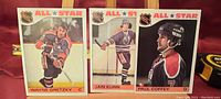 Front view showing Wayne Gretzky, Jari Kurri, and Paul Coffey hockey cards from the 1980s in Edmonton Oilers uniforms.