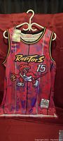 Front view of Toronto Raptors basketball jersey with raptor logo, number 15, and attached tag.