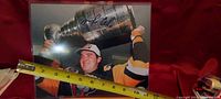 Photo of signed image showing Mario Lemieux holding the Stanley Cup with a measuring tape to show size.