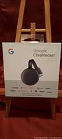Front view of sealed Google Chromecast box showing product and compatible streaming services