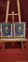 Two Joe Sakic rookie hockey cards displayed on a wooden easel; cards in protective plastic sleeves