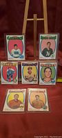 All seven 1971-72 OPC hockey rookie cards displayed on a stand, showing colorful oval backgrounds with player photos and team names.
