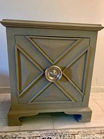 Front view of the wooden cabinet showing the decorative geometric panel on the door and central knob.