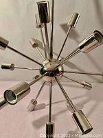 Close-up top view of the central sphere and radiating metal arms with bulb sockets