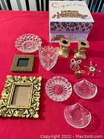 Photo of all items displayed on a red cloth including candle holders, crystal dishes, frames, wire angels, and leopard shoe box