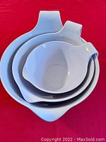 Stacked view of three white Curtis Stone mixing bowls showing nesting and handles