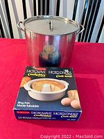 Photo showing large stainless steel pot with lid on a red surface with microwave cake ring pan box in front