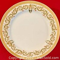 Photo showing the full top view of a Limoges dish with gold and floral decorative border on white background.