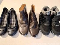 Three pairs of new size 9 shoes: black fashion sneakers with fur lining, metallic brown ankle boots, and black slip-on flats with plaid lining.