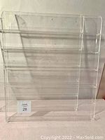 Front view of one plexiglass nail polish shelving unit showing horizontal shelves and clear material.
