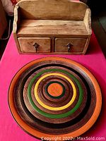 Wooden shelf with two drawers and circular decorative painted plate together on red surface
