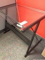 Close-up of glass top with metal frame and leg structure showing support and corners of desk