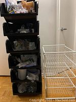 Six black stackable storage cubbies stacked vertically, filled with assorted items not included.