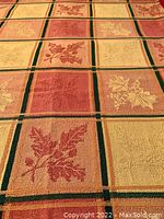 Close-up image showing the fall motif tablecloth fabric pattern with oak leaves and grid lines in autumn colors.