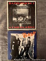 Front covers of two vinyl albums by The Clash, one album is Sandinista! with band standing against a brick wall, the other shows three band members against a blue background.