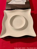 Photo of a white square porcelain vegetable and dip platter showing the platter with wavy edges and a round center bowl for dip.
