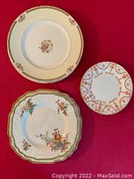 Two beige round plates and two smaller plates with floral borders on red background