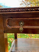 Close-up of drawer front showing carved rope-edge molding and metal drop pull