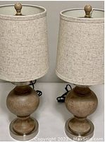 Photo of two matching natural wood tone table lamps with fabric shades, showing base design and overall height.