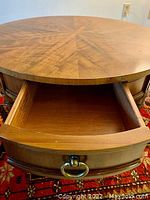 Close-up of the drawer pulled open showing interior wood and brass ring pull handle on curved drawer front.